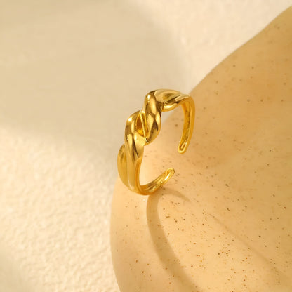 Bague ouverte torsadée en acier inoxydable et or jaune debout.