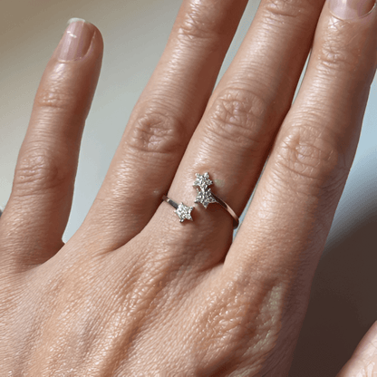 Bague ouverte trio d'étoiles en argent 925 rhodié et zircons sertis grains portée au doigt d'une femme vue de proche.