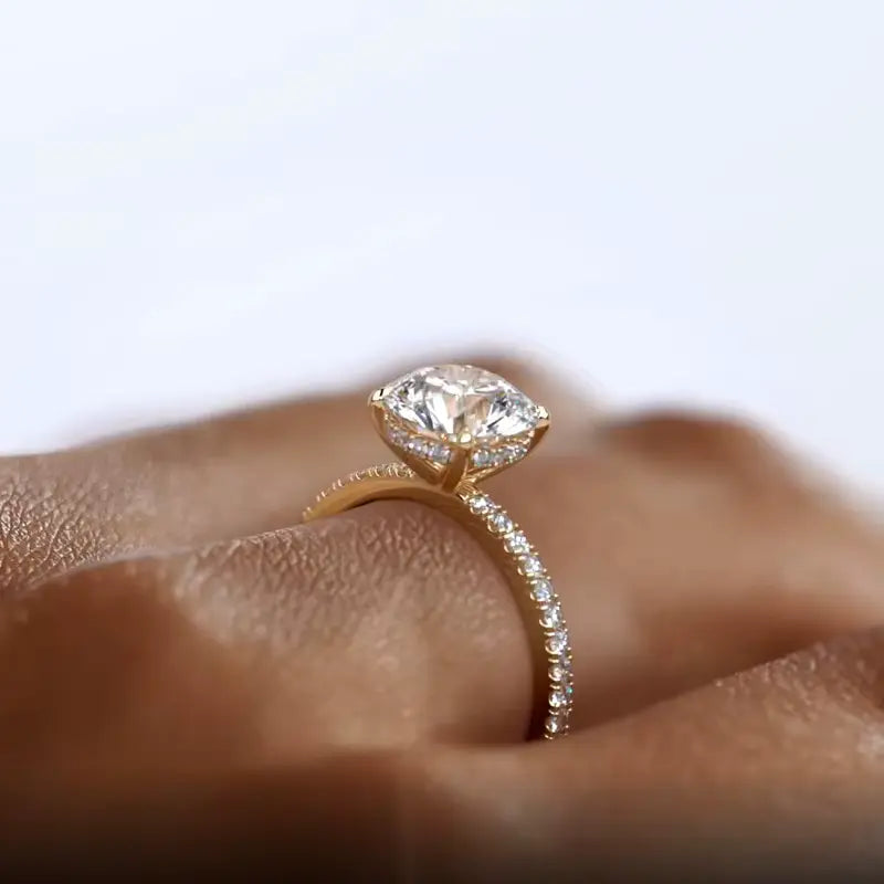 Bague solitaire Artemis en argent 925 plaqué or jaune et diamants portée au doigt d'une femme vue de proche.