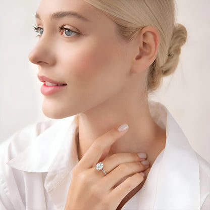 Bague solitaire en or blanc et diamant synthétique portée au doigt d'une femme blonde.