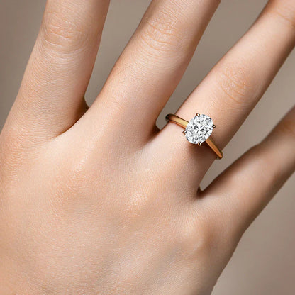 Bague solitaire en or jaune et diamant synthétique portée au doigt d'une femme vue du dessus.