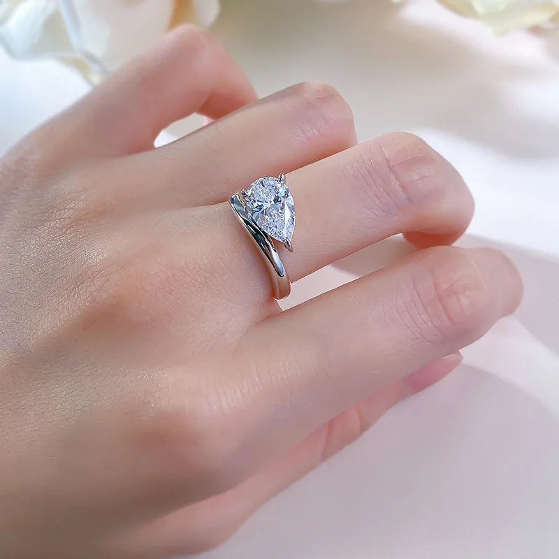 Bague solitaire courbée en or blanc et diamant synthétique portée au doigt d'une femme.