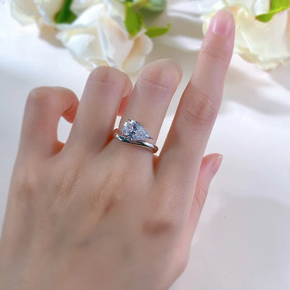 Bague solitaire courbée en or blanc et diamant synthétique portée au doigt d'une femme vue du dessus.