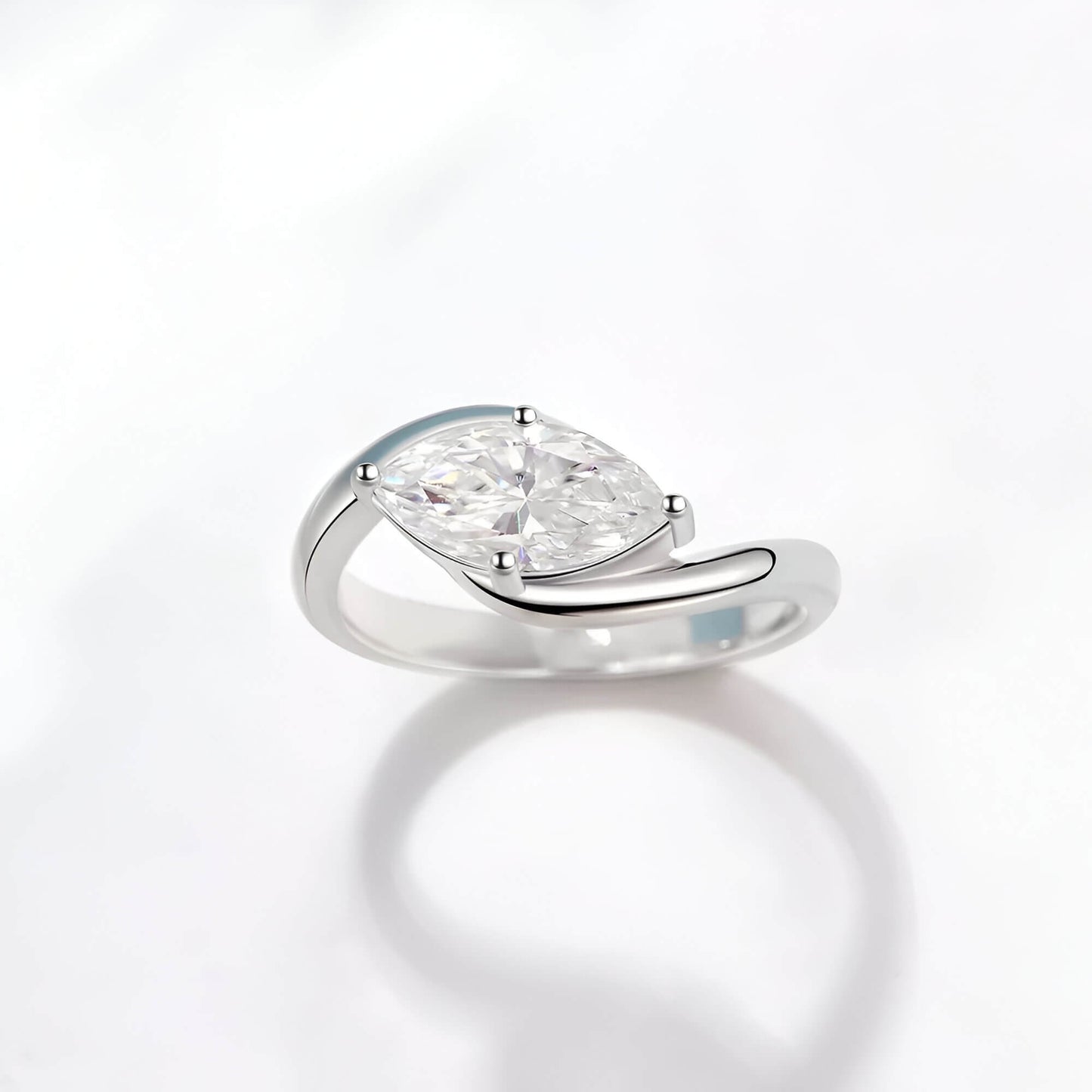 Bague solitaire courbée en or blanc et diamant synthétique sur fond blanc.