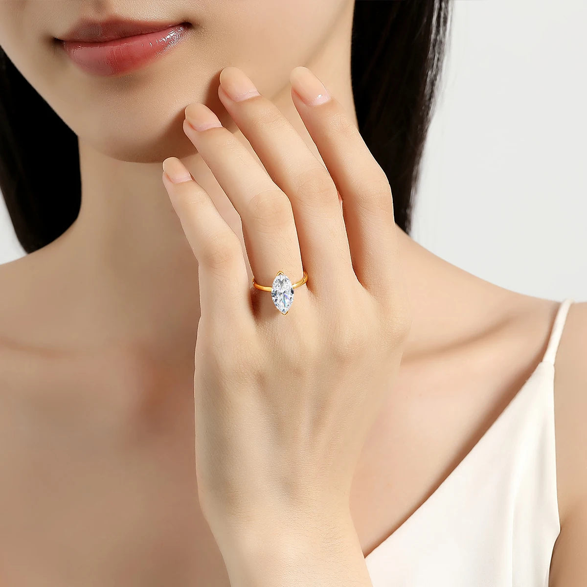 Bague solitaire diamant marquis serti barre en or jaune 14K portée au doigt d'une femme vue de face.
