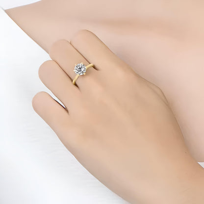 Bague solitaire en or jaune et oxyde de zirconium portée au doigt d'une femme.