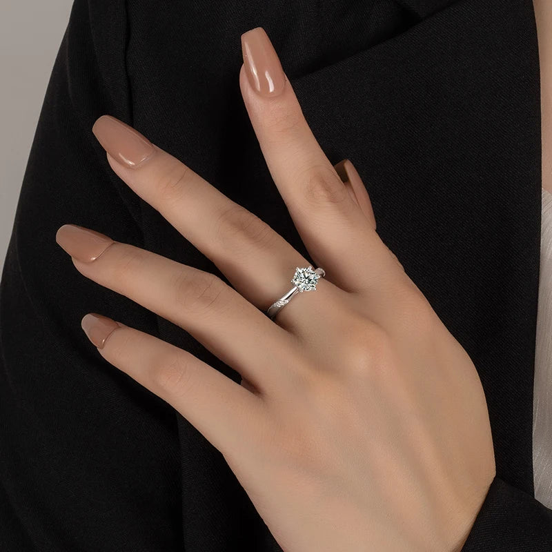 Bague solitaire en or blanc sertie de diamants synthétique et naturel portée au doigt d'une femme.