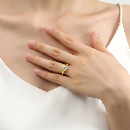 Bague solitaire granulé en or jaune et diamant synthétique portée au doigt d'une femme.