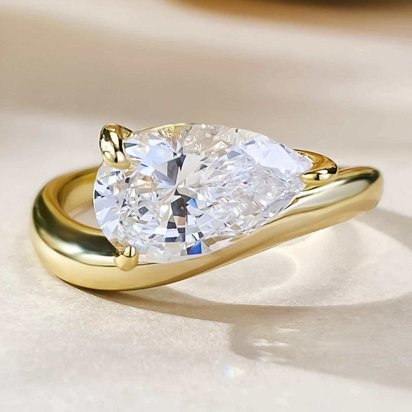 Bague solitaire incurvée en argent 925 plaqué or jaune et diamant scintillant forme goutte vue de proche.
