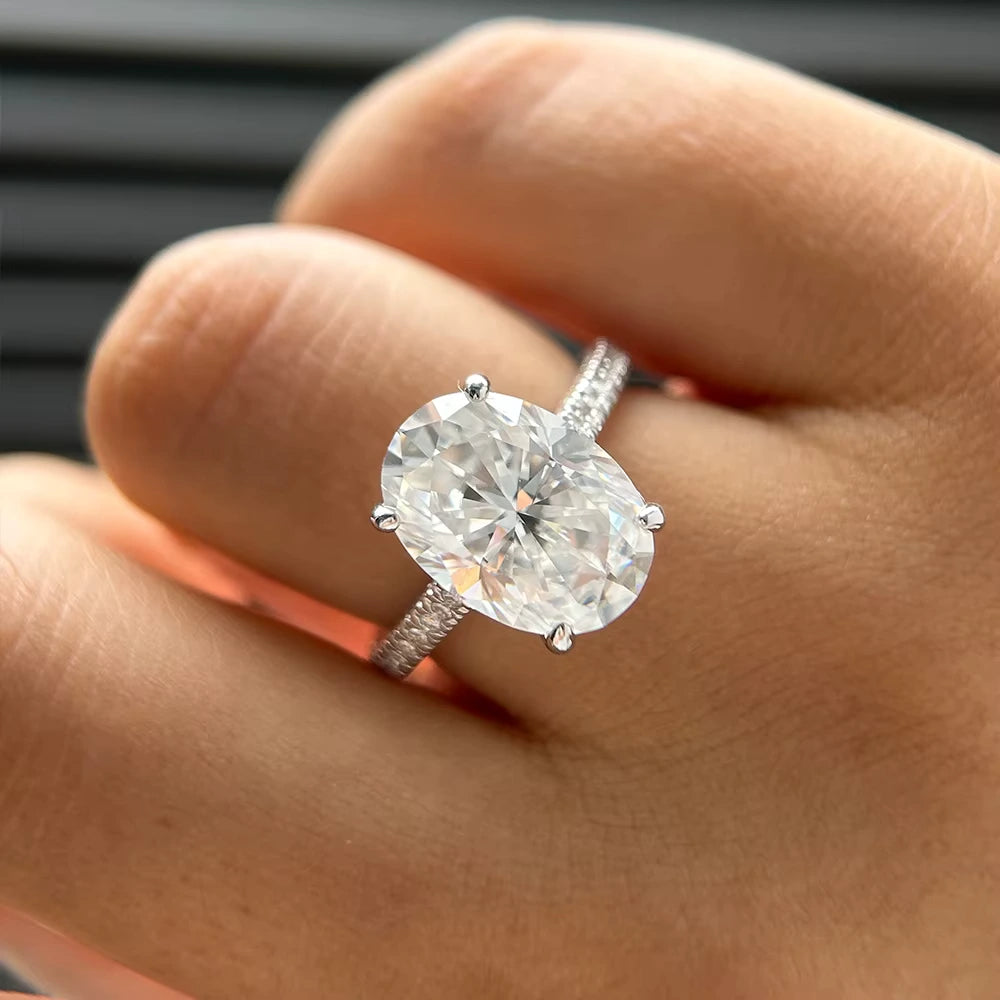 Bague solitaire en or blanc et diamants synthétiques portée au doigt d'une femme vue du dessus.