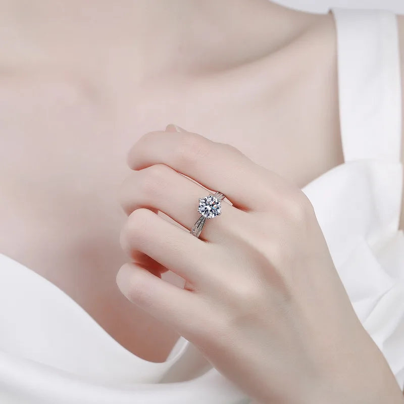 Bague solitaire en or blanc et diamant synthétique portée au doigt d'une femme.
