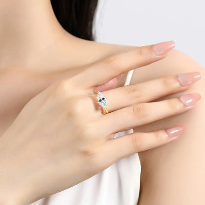 Bague solitaire navette serti quatre griffes en or jaune et diamant synthétique portée au doigt d'une femme.