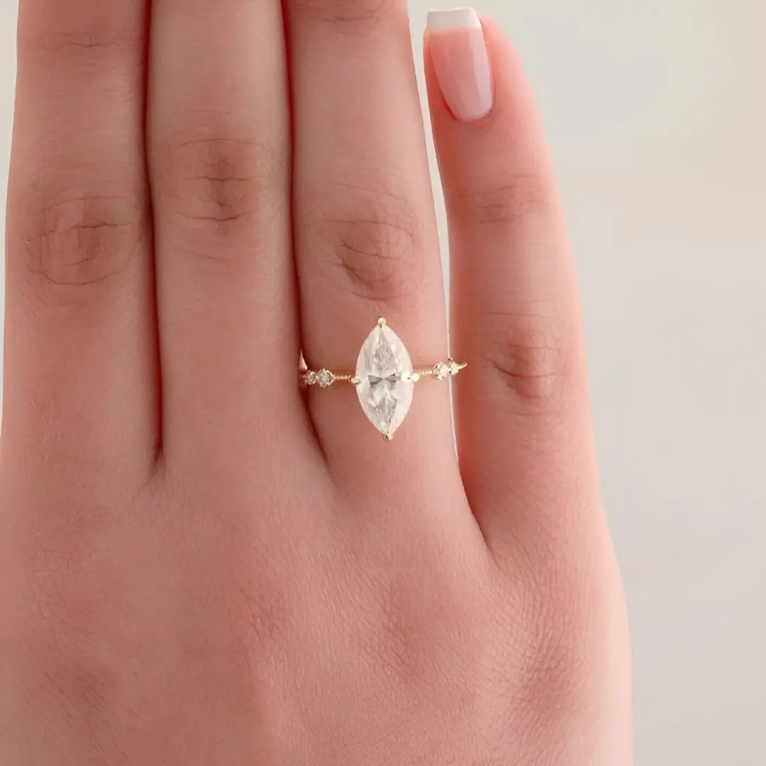Bague solitaire en or jaune et oxyde de zirconium portée au doigt d'une femme vue du dessus.
