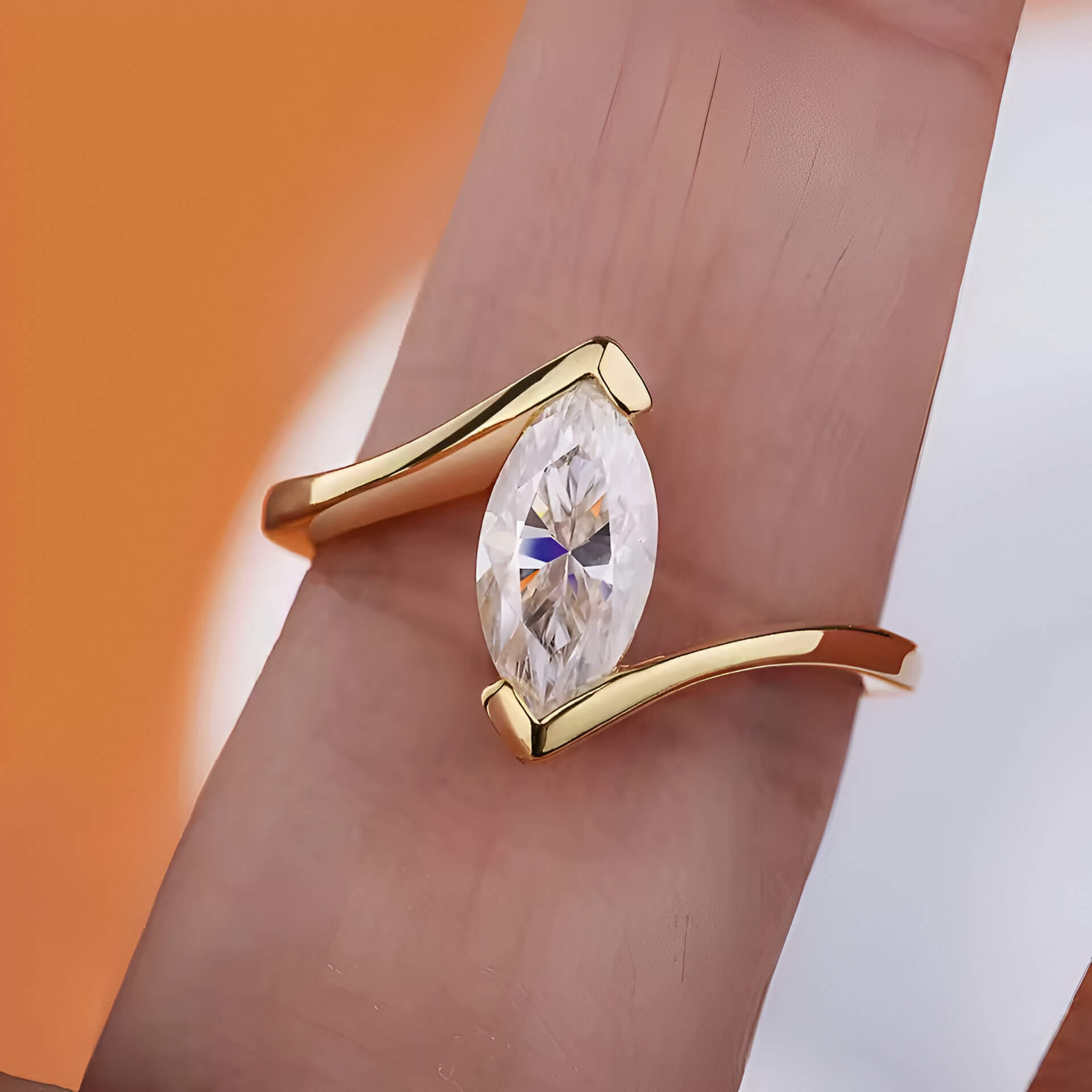 Bague solitaire serti barre Amina en argent 925 plaqué or jaune chaleureux et diamant navette montrée par un doigt vue de face.