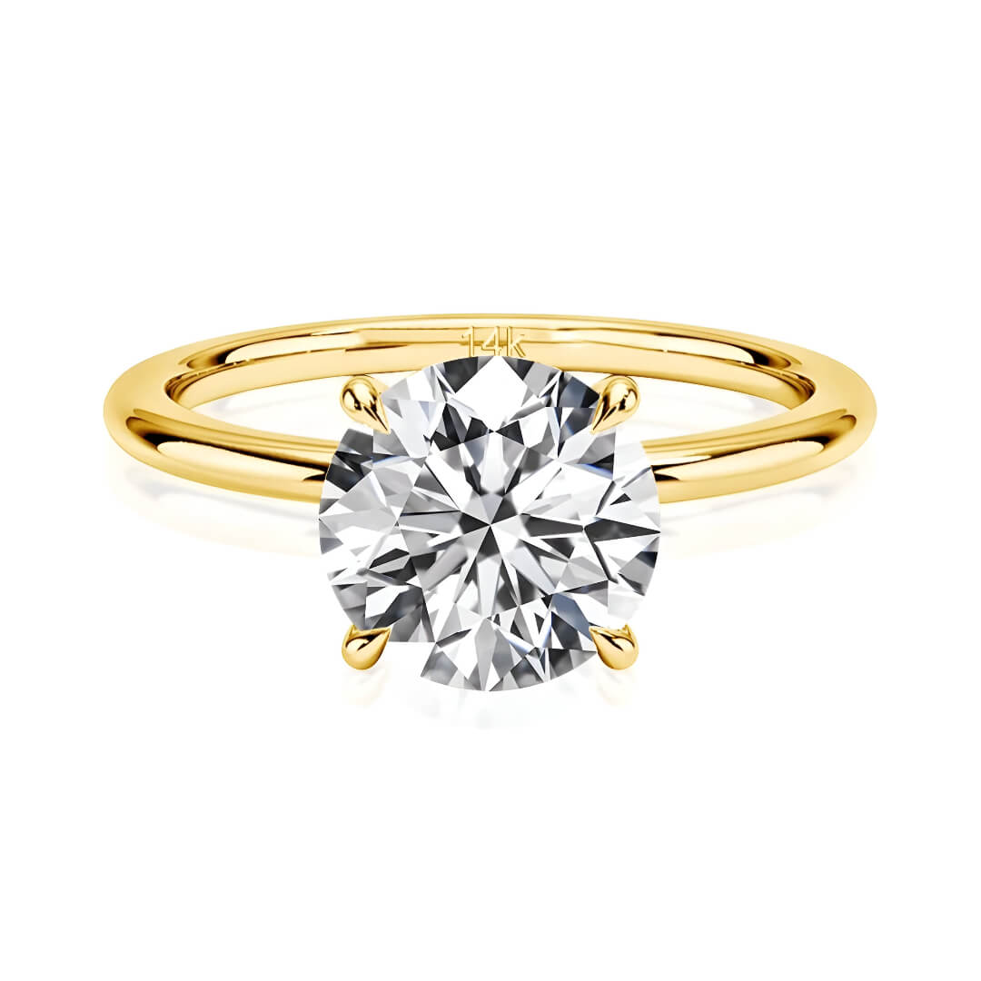 Bague solitaire quatre griffes en or jaune et diamant synthétique sur fond blanc.