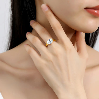 Bague solitaire serti semi-clos en or jaune et diamant synthétique portée au doigt d'une femme.