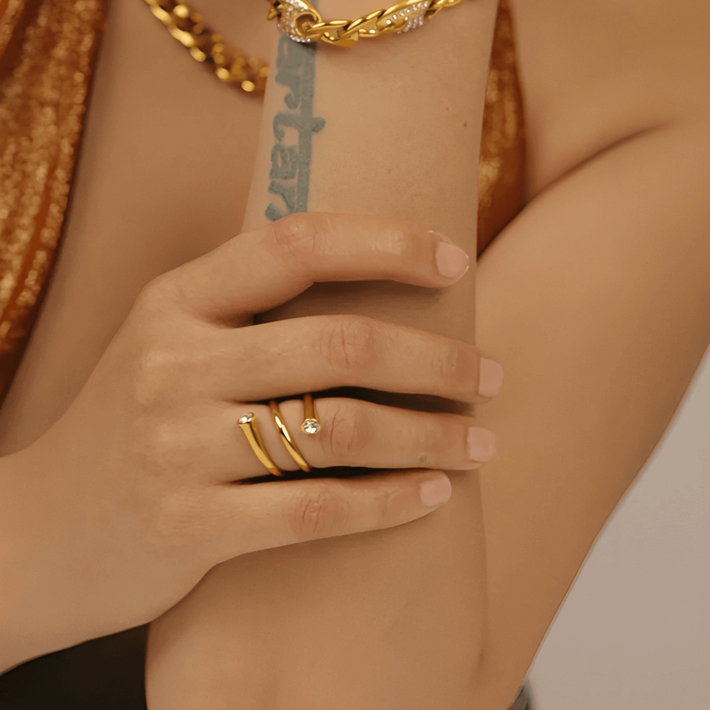 Bague tourbillon style atypique Thalissa en acier plaqué or jaune 14K et cristal serti clos portée au doigt d'une femme vue de loin.