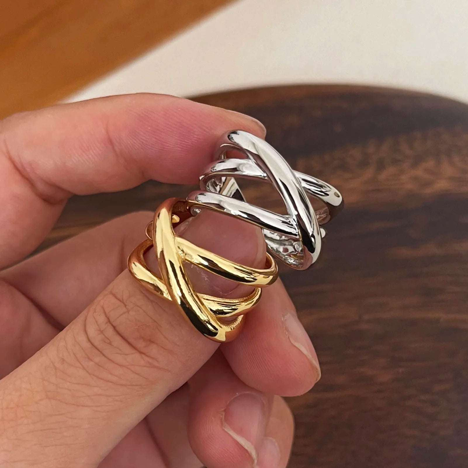 Variantes de la bague triple croisement ajustable en argent 925 plaqué or jaune ou or blanc montrées au doigt d'une femme vue de face.
