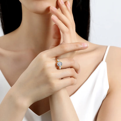 Bague triple pierre en or jaune et diamants synthétiques portée au doigt d'une femme.