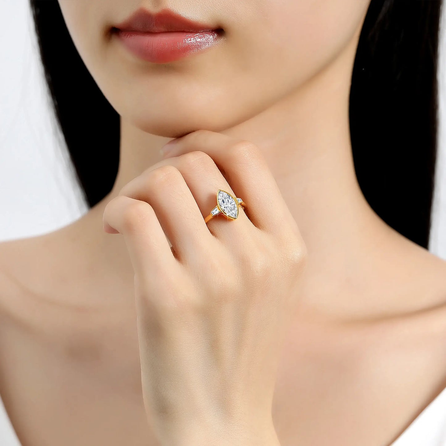 Bague trois pierres Lauretta en or jaune 14K et diamant marquis étincelant de 2CT portée au doigt d'une femme vue de face.