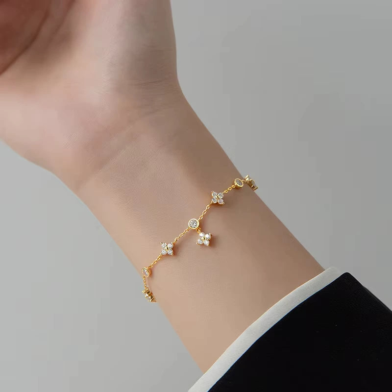 Bracelet breloque fleur en argent 925 plaqué or jaune lumineux et diamants porté au poignet d'une femme vue de face.