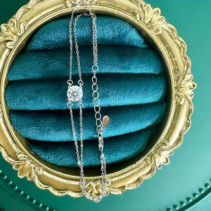 Bracelet chaîne double argentée en argent 925 plaqué or blanc et moissanite solitaire vue du dessus.