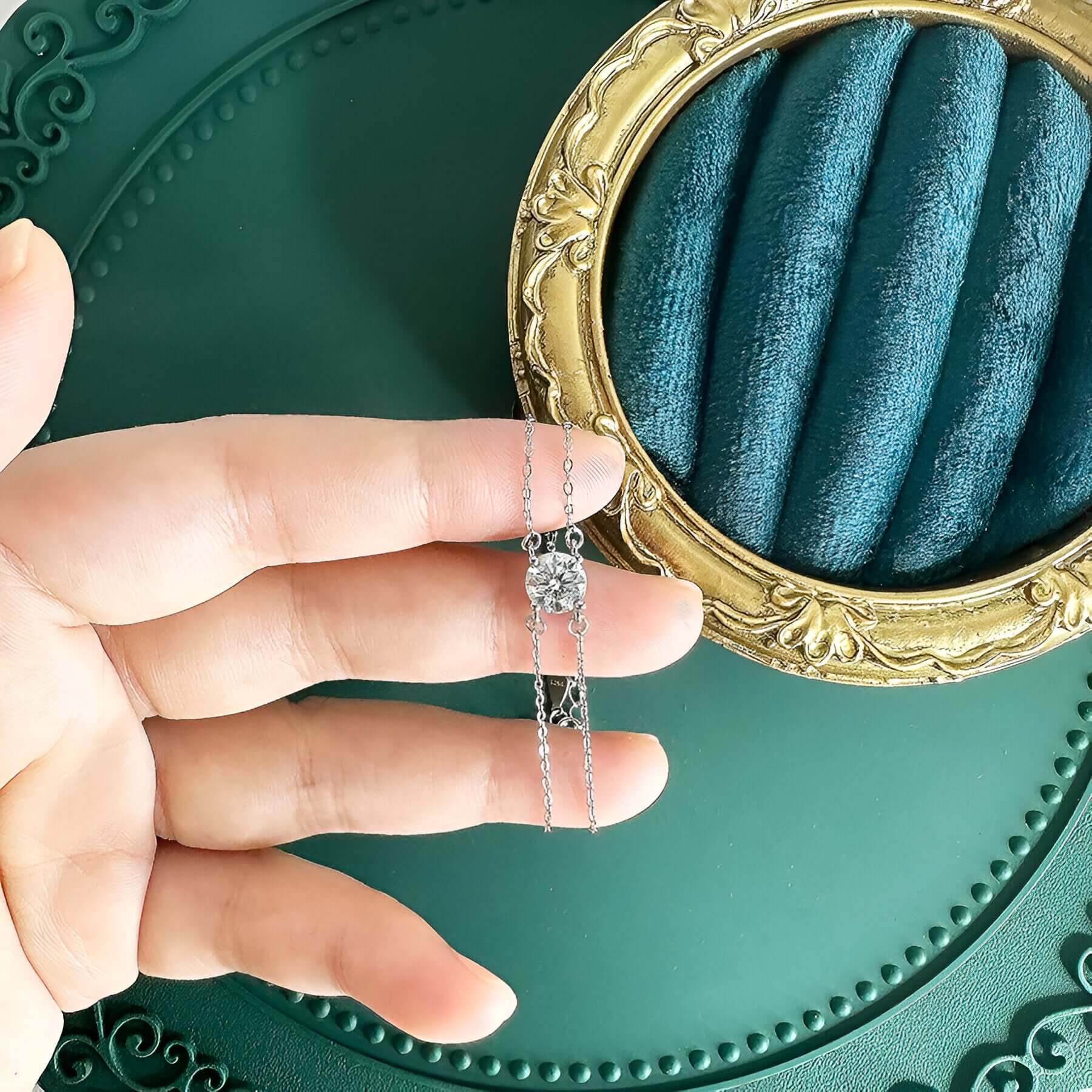Bracelet chaîne double argentée en argent sterling 925 plaqué or blanc et moissanite solitaire sur les doigts d'une main de femme vue du dessus.