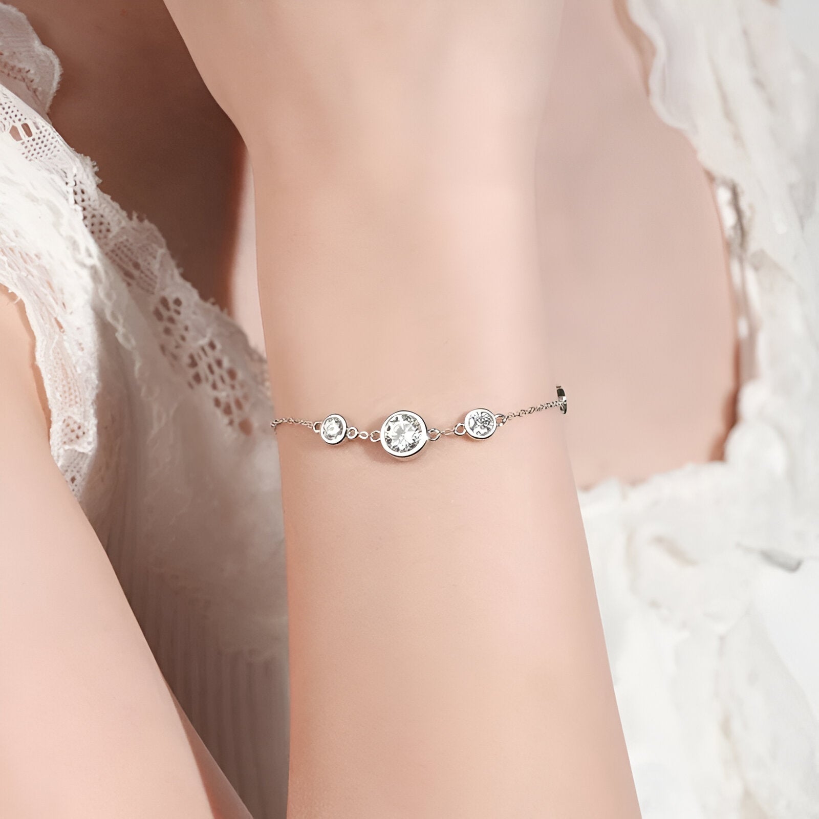 Bracelet chaîne fine en argent 925 plaqué or blanc et moissanites porté au poignet d 'une femme vue de face.