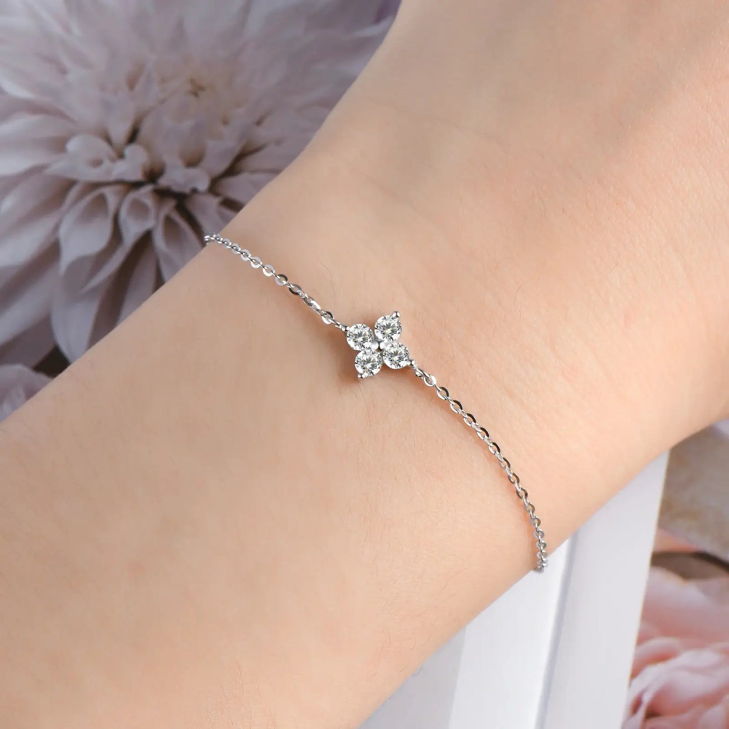 Bracelet chaîne fine fleur pavée en argent 925 plaqué or blanc raffiné et moissanites porté au poignet d'une femme vue de face.