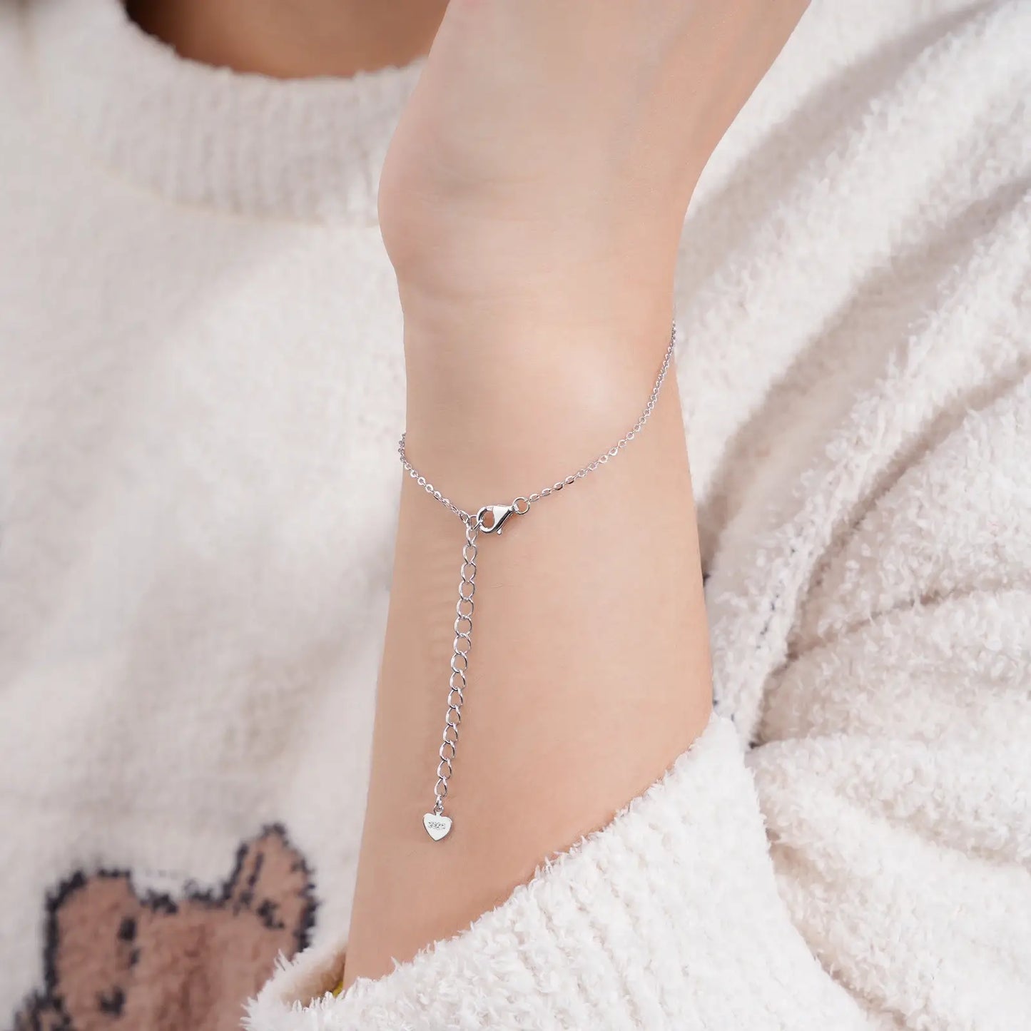 Bracelet chaîne fine fleur pavée en argent sterling 925 plaqué or blanc et moissanites porté au poignet d'une femme vue de dos.