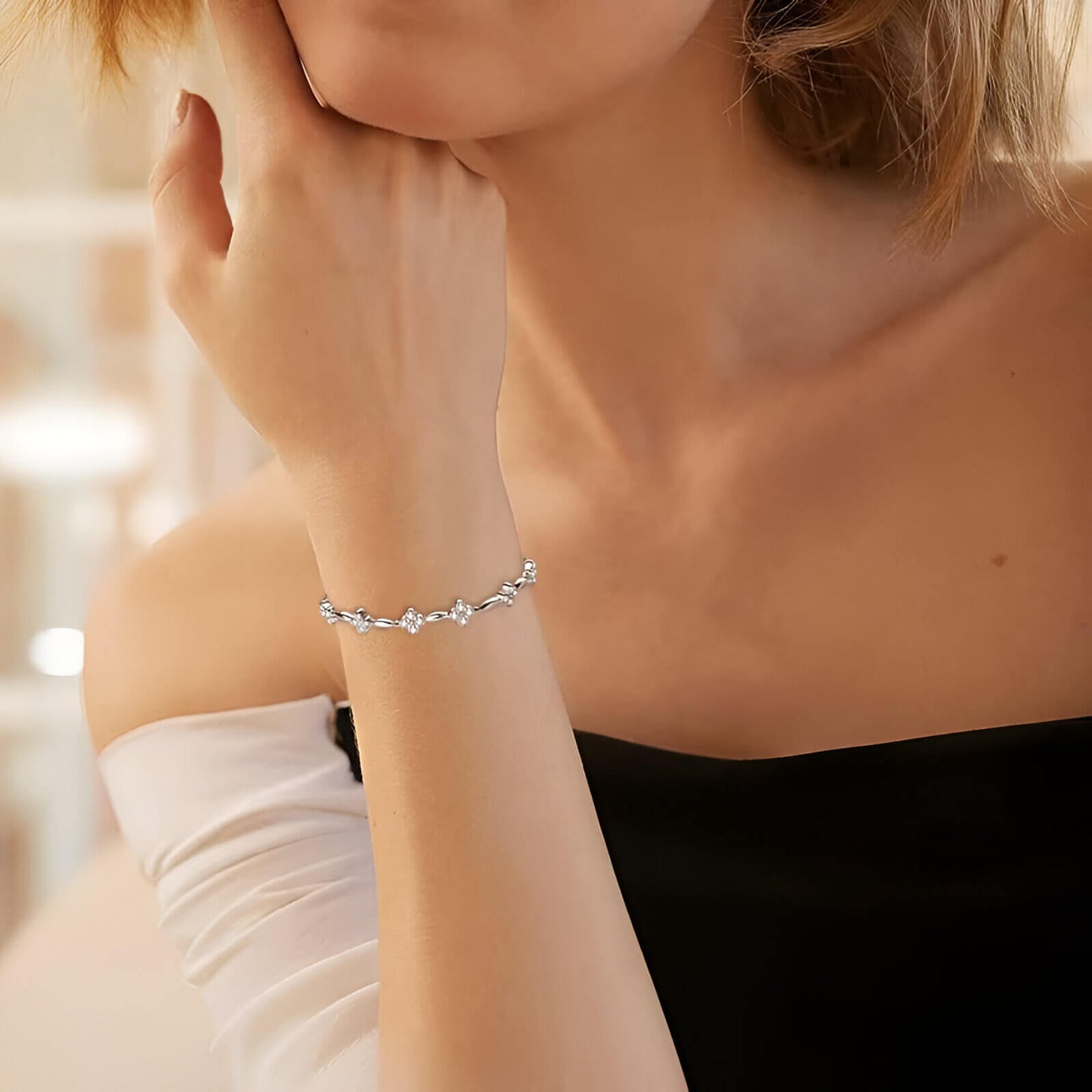 Bracelet chaîne fleur en argent 925 plaqué or blanc et moissanites scintillantes porté au poignet d'une femme vue de loin.