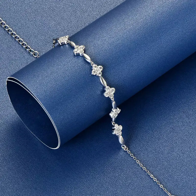 Bracelet chaîne fleur en argent sterling 925 plaqué or blanc et moissanites posé sur une surface bleue.