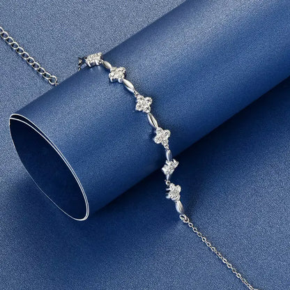 Bracelet chaîne fleur en argent sterling 925 plaqué or blanc et moissanites posé sur une surface bleue.