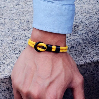 Bracelet double cordon jaune et fermoir crochet en zinc porté au poignet d'un homme.