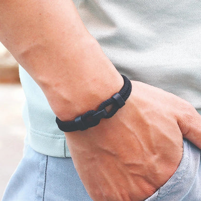 Bracelet double cordon noir fermoir loquet pivotant porté au poignet d'un homme vue de proche.