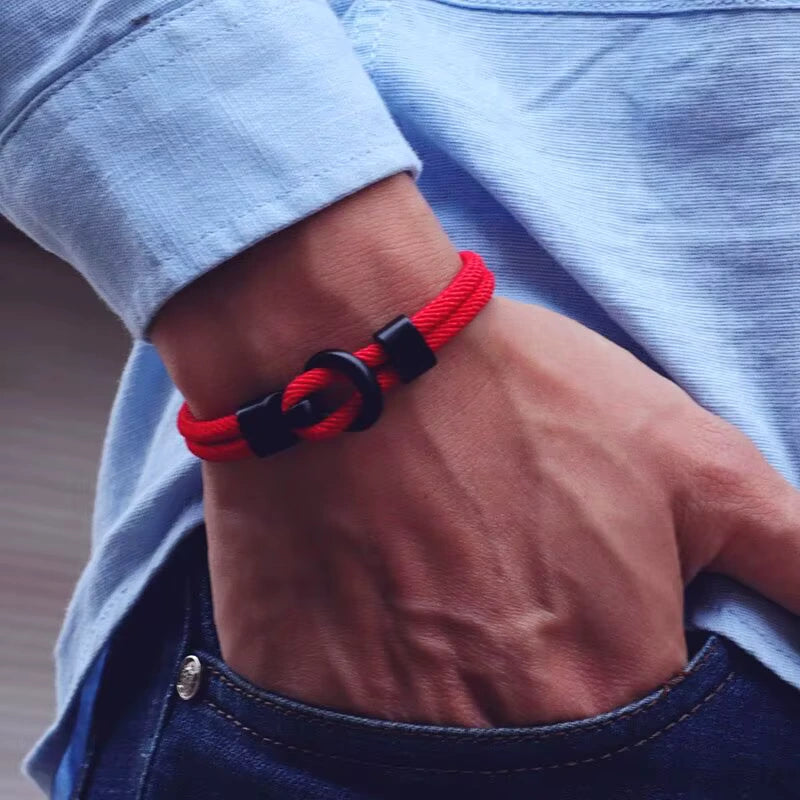 Bracelet double cordon rouge et fermoir crochet en zinc porté au poignet d'un homme.