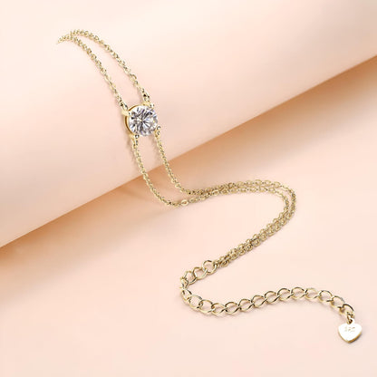 Bracelet double maile dorée en argent 925 plaqué or jaune et diamant solitaire posée sur un cylindre.