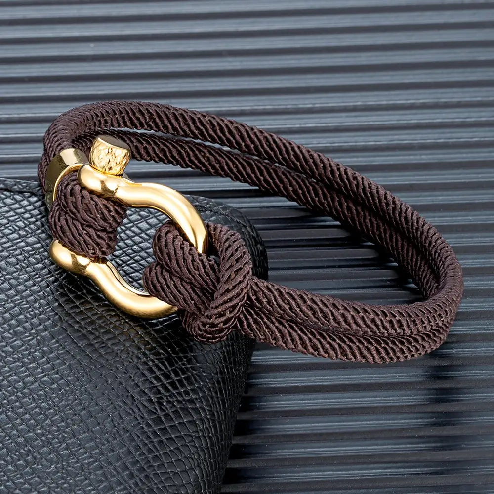 Bracelet cordon marron fer à cheval en acier doré posé.