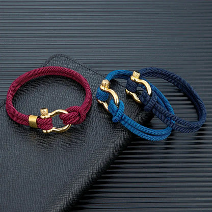 Bracelets cordons rouge bordeaux, bleu et bleu foncé fer à cheval en acier doré posés.