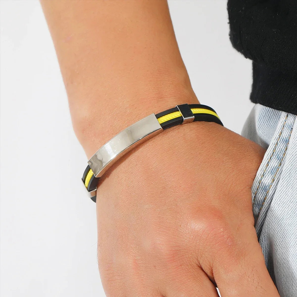 Bracelet gourmette en acier inoxydable plaqué titane blanc et silicone noir variante jaune porté au poignet d'un homme.