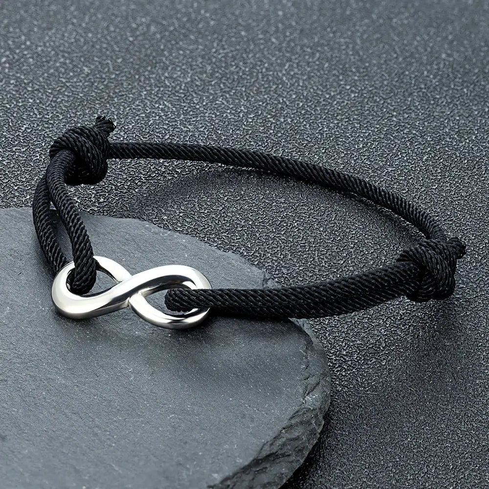 Bracelet infini ajustable en acier inoxydable blanc et cordon noir posé.
