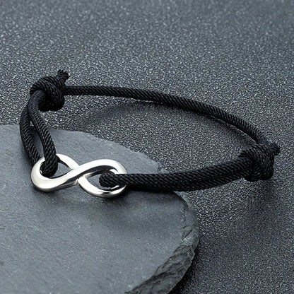 Bracelet infini ajustable en acier inoxydable blanc et cordon noir posé.
