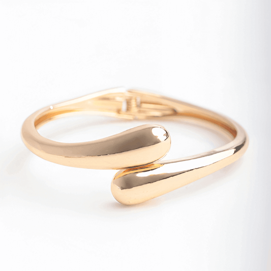 Bracelet jonc goutte d'eau en or jaune sur fond blanc.