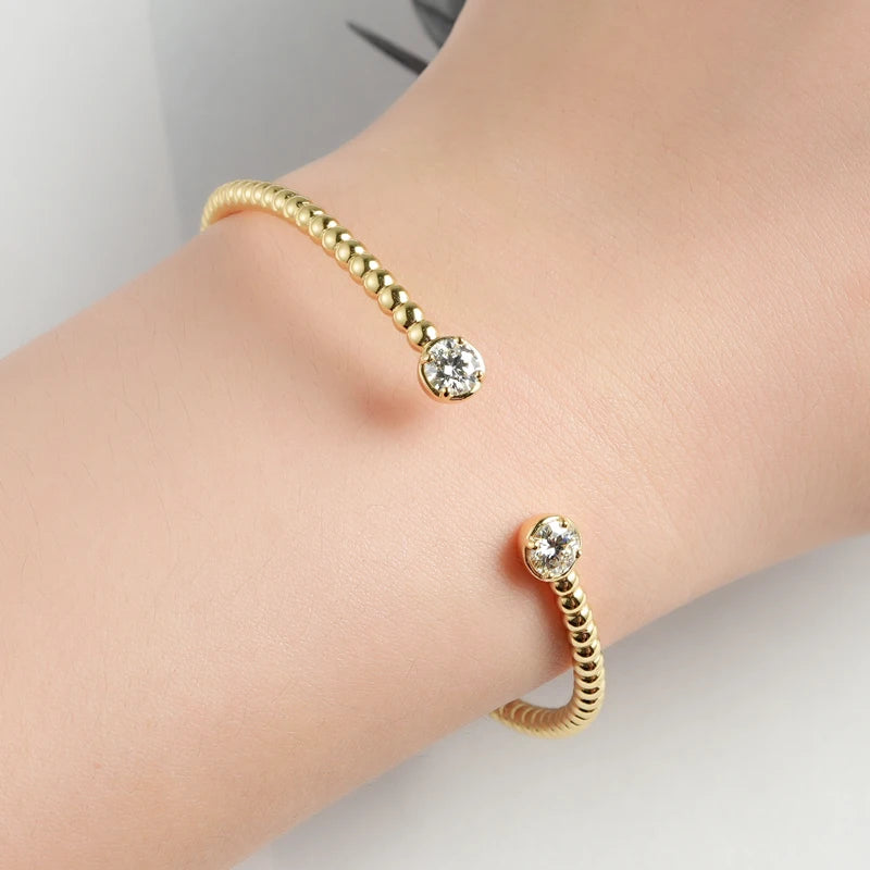 Bracelet jonc granulé en argent 925 plaqué or jaune et double diamants forme ronde sertis quatre griffes porté au poignet d'une femme.