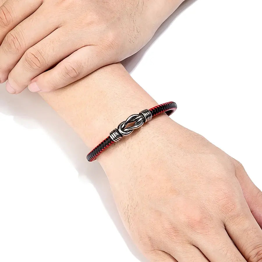Bracelet liaison nœud argenté en cuir noir&rouge tressé et acier inoxydable plaqué titane porté au poignet d'un homme.