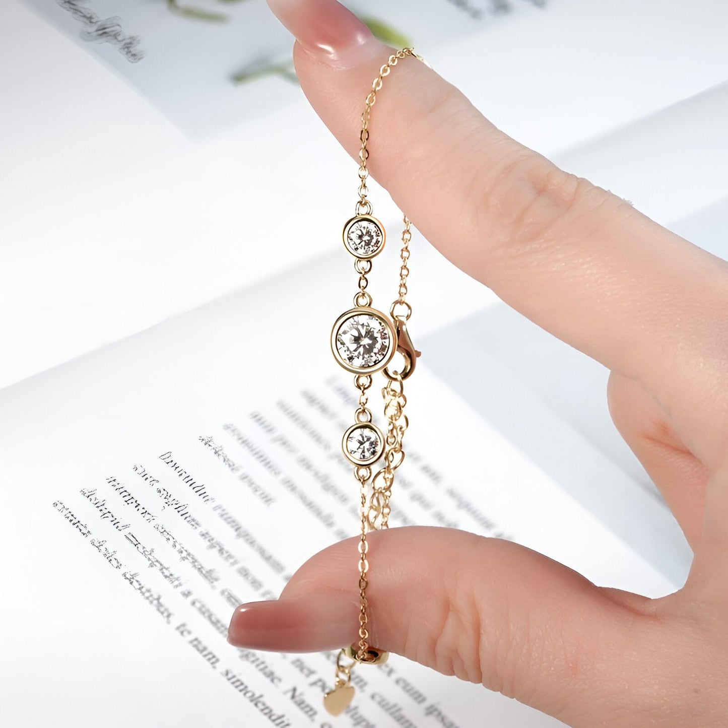 Bracelet maille Elydia en argent 925 plaqué or jaune et diamants étincelants entre les doigts d'une femme vue de proche.