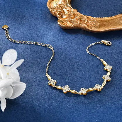 Bracelet maille fine fleur en argent 925 plaqué or jaune lumineux et diamants à plat sur une surface bleue.