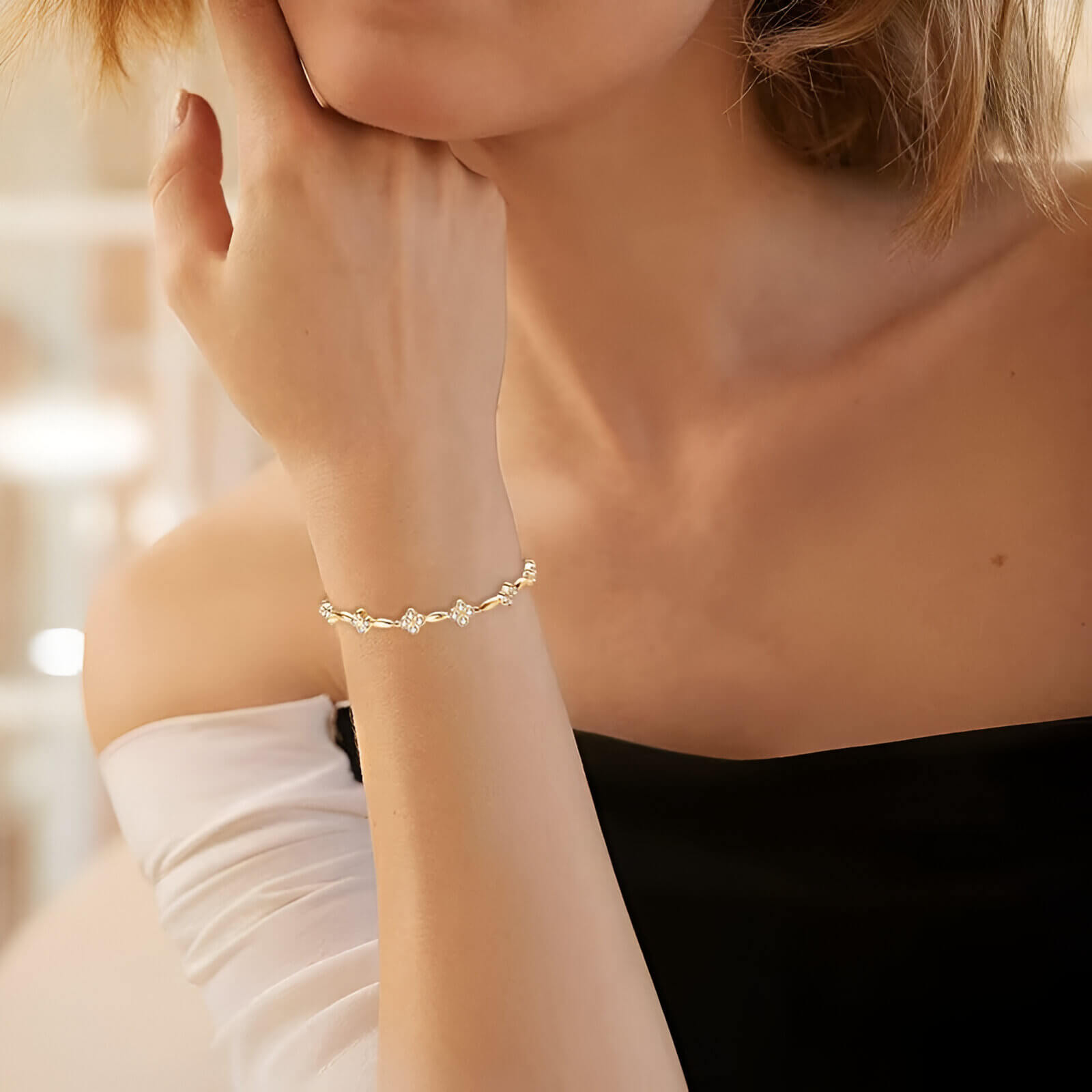 Bracelet maille fine fleur en argent sterling 925 plaqué or jaune et diamants porté au poignet d'une femme vue de loin.