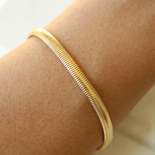 Bracelet maille serpent en argent sterling 925 plaqué or jaune porté au poignet d'une femme vue de proche.