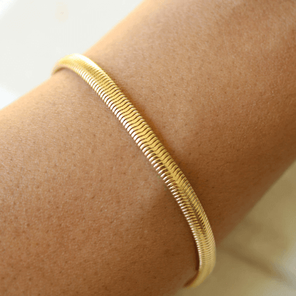Bracelet maille serpent en argent sterling 925 plaqué or jaune porté au poignet d'une femme vue de proche.